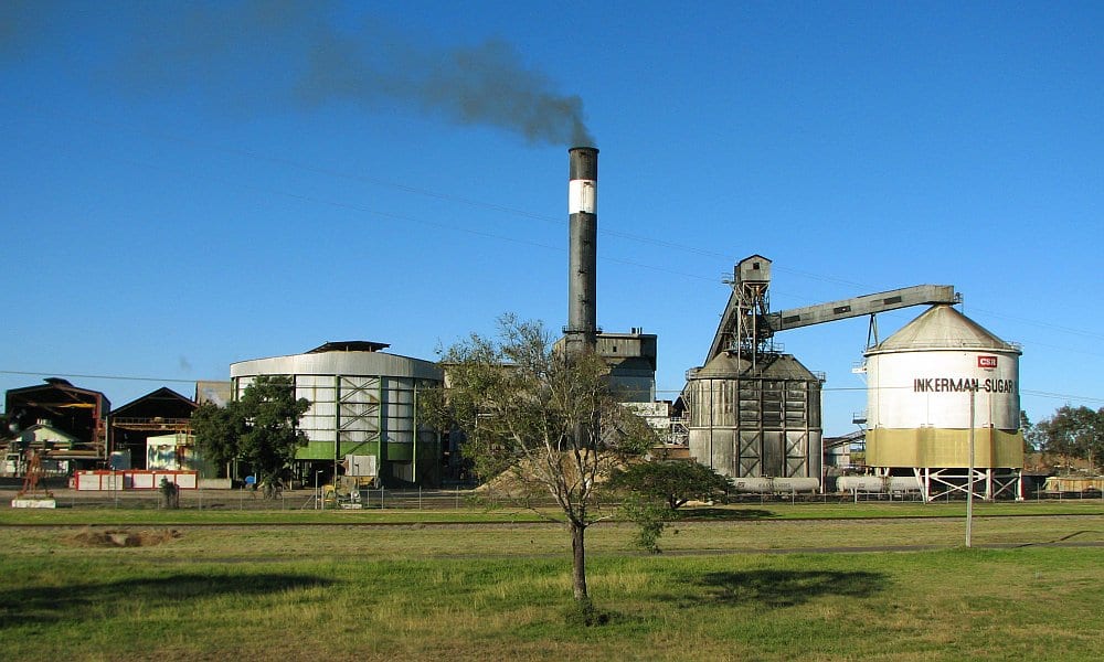 Cane sugar mill with a tall smokestack and a bulk sugar storage silo
